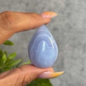 May include: A teardrop-shaped blue lace agate crystal with white and light blue banding.