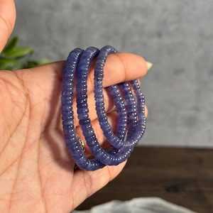 Puede incluir: Una pila de tres pulseras de piedras azules hechas de peque&ntilde;as cuentas redondas.