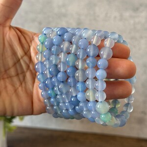 Puede incluir: Una pila de pulseras de &aacute;gata azul con un degradado de color azul claro y blanco. Las pulseras est&aacute;n hechas de cuentas redondas y est&aacute;n apiladas unas sobre otras.