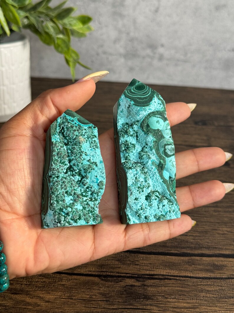 Puede incluir: Dos puntas de cristal de malaquita verde con un patr&oacute;n de remolino. Las puntas miden aproximadamente 5 cm de alto y se sostienen en una mano.