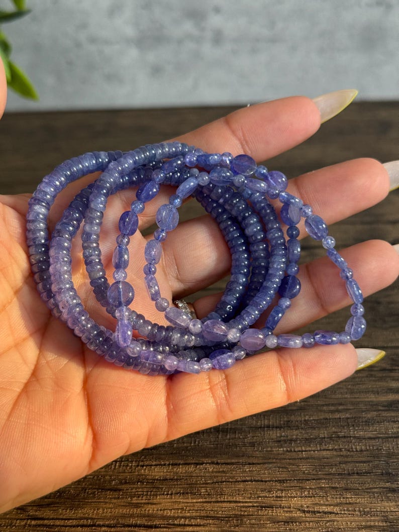 Puede incluir: Un conjunto de cinco pulseras de cuentas de piedras preciosas de color p&uacute;rpura. Las pulseras est&aacute;n hechas con cuentas peque&ntilde;as y redondas y est&aacute;n apiladas unas sobre otras.