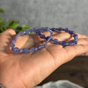 Puede incluir: Dos pulseras de piedras preciosas moradas con peque&ntilde;as cuentas redondas. Las pulseras est&aacute;n hechas de piedras naturales y est&aacute;n apiladas una encima de la otra.