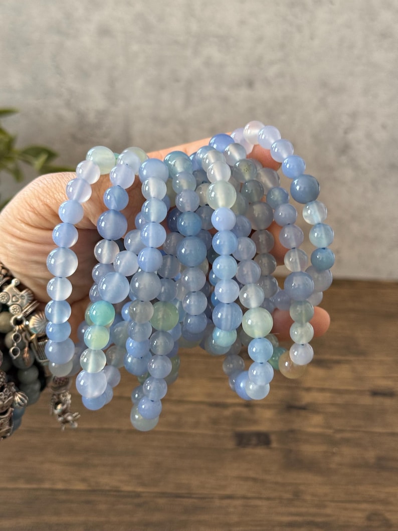 Puede incluir: Una pila de pulseras de cuentas de &aacute;gata azul y verde. Las pulseras est&aacute;n hechas con cuentas redondas y todas son del mismo tama&ntilde;o.