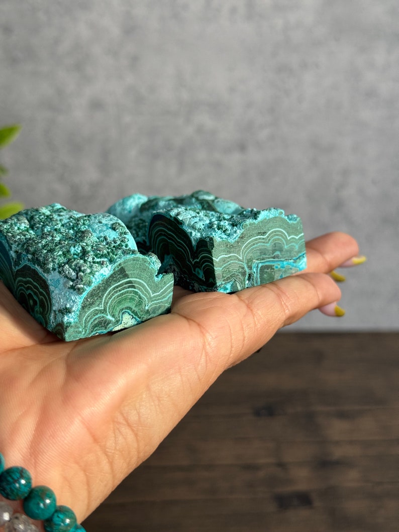 Puede incluir: Dos piezas de malaquita verde con un patr&oacute;n de bandas. La malaquita es una piedra natural con una superficie lisa y pulida.