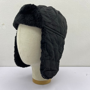 May include: Black quilted winter hat with faux fur ear flaps. The hat is made of a soft, warm material and is ideal for cold weather.