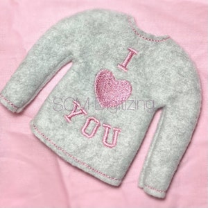 May include: A gray fleece sweater with pink embroidered lettering that says "I love you" and a pink heart.