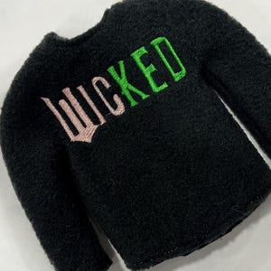 May include: Black fleece sweater with the word "WICKED" embroidered in pink and green.