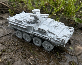 May include: A gray, detailed model of a military armored vehicle with a turret and a machine gun. The vehicle is on a muddy surface.