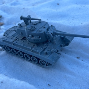 May include: A gray toy tank with a long barrel and a detailed turret. The tank is sitting on a white surface.
