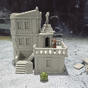 May include: A gray 3D printed miniature building with a balcony and a sign that reads "The Old Path". A small figure stands on the balcony, and a green and gold dice sits in the foreground.