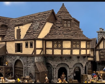 Può includere: Una dettagliata scena di un villaggio medievale in miniatura con edifici in pietra e a graticcio. Le strutture presentano schemi di colore marrone, beige e grigio, con uno sfondo di cielo blu. La scena comprende un'area di mercato con figure e bancarelle.