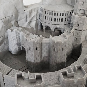 May include: A gray, detailed model of a castle with a tower and multiple walls. The castle is built on a rocky base.