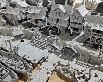 Puede incluir: Una escena de pueblo en miniatura con edificios pintados de gris, muelles de madera y pequeños barcos. La escena está ambientada en un terreno rocoso con un acabado pintado de gris.