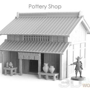 May include: A grayscale miniature model of a Japanese pottery shop with a tiled roof and a small figure of a samurai warrior. The shop has a wooden facade, with pottery displayed on small tables.