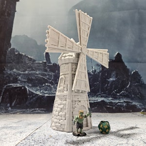 May include: A white, 3D printed miniature windmill with a stone base and a wooden blade design. The windmill is standing on a light wood surface with a green miniature figure and a green and black dice.