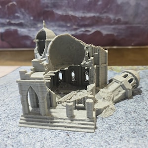 May include: A gray, 3D-printed model of a ruined building, possibly a cathedral or temple. The structure is partially collapsed, with visible arches, columns, and a dome. The model is detailed and shows signs of weathering.