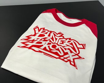 May include: White and red baseball tee shirt with the words "BUTTERED BROS" printed in red on the front.