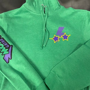 Puede incluir: Sudadera con capucha verde con un rayo morado y dos estrellas amarillas en la parte delantera. La manga izquierda tiene un gráfico morado y negro que dice "Gator Golf, Mow's".