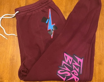 May include: Burgundy sweatpants with a pink "Fizza Blast" graphic on the leg and a blue lightning bolt with a top hat and bow tie on the back.