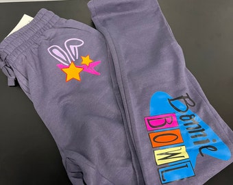 May include: Purple sweatpants with a pink bunny rabbit and stars on the left leg and the words "Bonnie Bowl" in colorful letters on the right leg.
