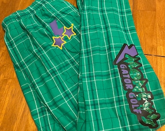 May include: Green and white plaid pajama pants with a purple and yellow graphic of a lightning bolt and the text "ZOMBIES GATOR GOLF".
