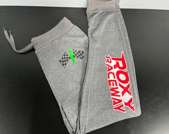 May include: Gray sweatpants with a checkered flag and a green figure on one leg and the red text "ROXY RACEWAY" on the other leg.