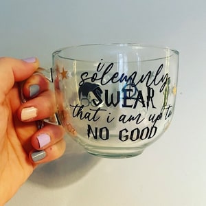 May include: A clear glass mug with a black and white graphic that reads "I solemnly swear that I am up to no good". The graphic is surrounded by gold stars.
