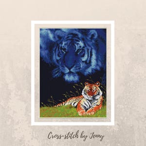 May include: Cross-stitch pattern featuring a blue tiger with a smaller orange tiger in the foreground. The blue tiger is in the background and appears to be a ghostly image. The orange tiger is lying down in a grassy area.