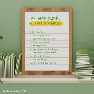 May include: A white framed classroom rules poster with the text "MS. ANDERSON'S CLASSROOM RULES" in green and yellow lettering. The rules are listed in black text: 1. Do your best, 2. Be ready to learn, 3. Eyes forward and listen, 4. Raise your hand, 5. Be respectful, 6. Say please and thank you, 7. Keep hands to yourself, 8. Follow directions, 9. Try new things, 10. Work hard and have fun.