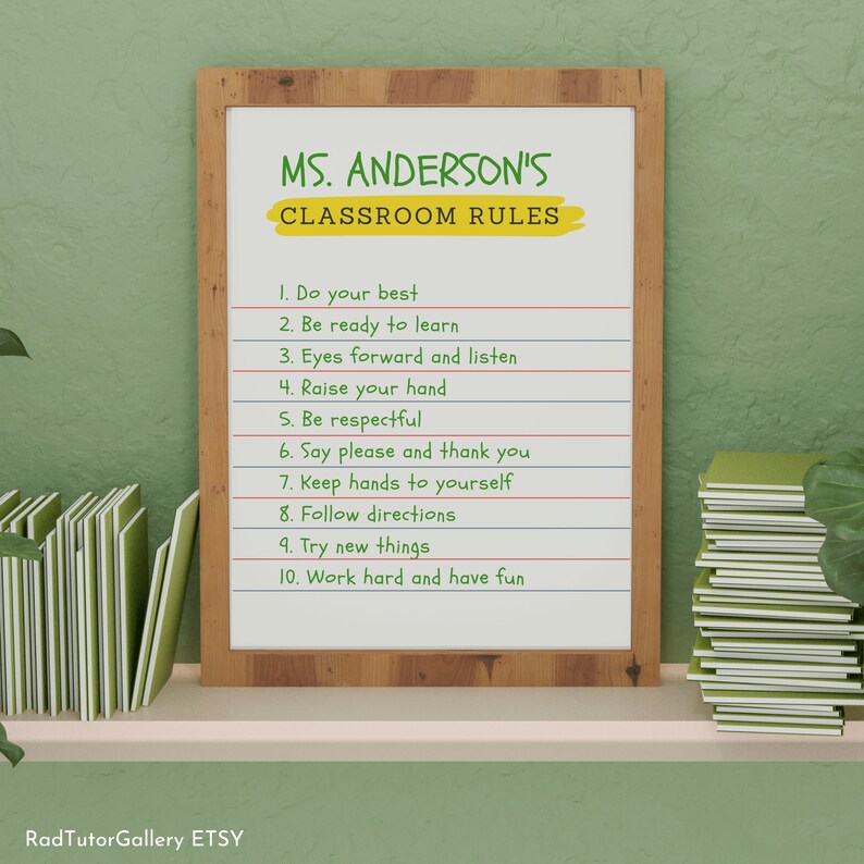 May include: A white framed classroom rules poster with the text "MS. ANDERSON'S CLASSROOM RULES" in green and yellow lettering. The rules are listed in black text: 1. Do your best, 2. Be ready to learn, 3. Eyes forward and listen, 4. Raise your hand, 5. Be respectful, 6. Say please and thank you, 7. Keep hands to yourself, 8. Follow directions, 9. Try new things, 10. Work hard and have fun.