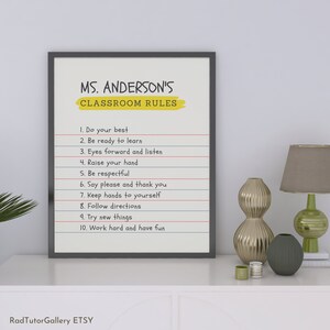 May include: A black framed classroom rules poster with a yellow title that reads "MS. ANDERSON'S CLASSROOM RULES". The poster lists ten rules for students, including "Do your best", "Be ready to learn", "Eyes forward and listen", "Raise your hand", "Be respectful", "Say please and thank you", "Keep hands to yourself", "Follow directions", "Try new things", and "Work hard and have fun".