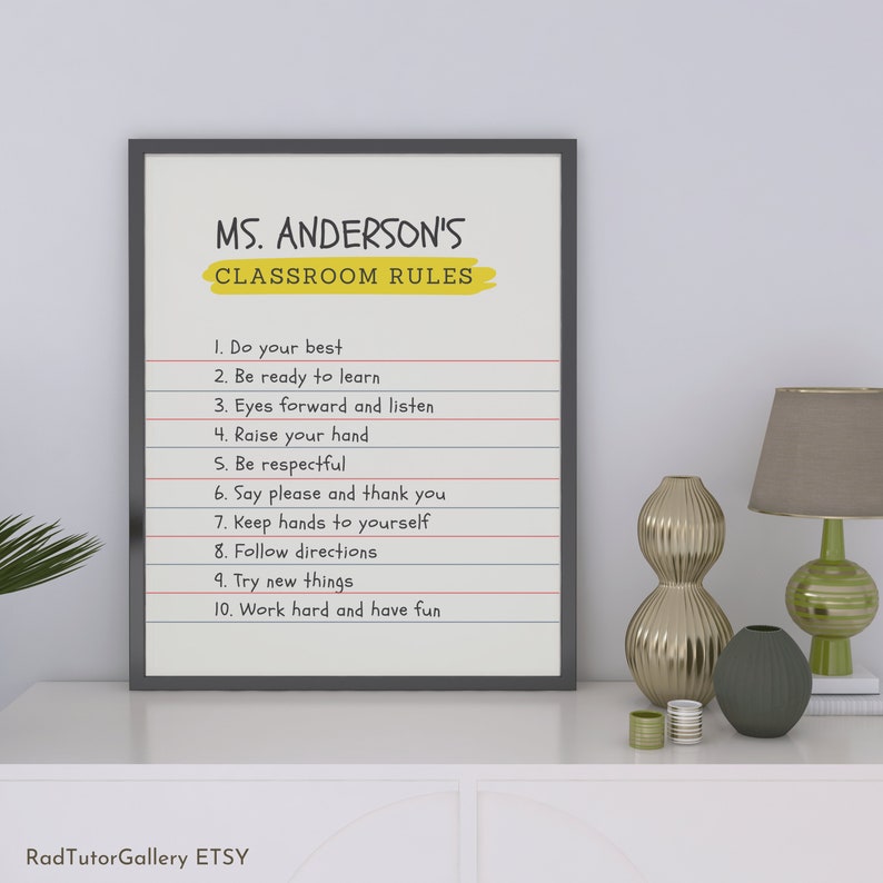 May include: A black framed classroom rules poster with a yellow title that reads "MS. ANDERSON'S CLASSROOM RULES". The poster lists ten rules for students, including "Do your best", "Be ready to learn", "Eyes forward and listen", "Raise your hand", "Be respectful", "Say please and thank you", "Keep hands to yourself", "Follow directions", "Try new things", and "Work hard and have fun".