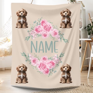 May include: A personalized throw blanket featuring a floral wreath with pink roses and green leaves. Four brown and white dogs are sitting around the wreath. The blanket is beige and has the word "NAME" in the center.