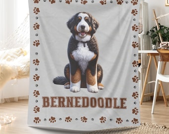 May include: A white throw blanket with a brown border featuring paw prints. The center of the blanket features a Bernedoodle dog sitting with the text "BERNEDoodle" in brown letters. The blanket is personalized with your dog's name.