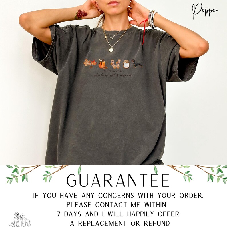 May include: Dark gray t-shirt with a fall-themed graphic. The design includes leaves, pumpkins, socks, and a dachshund, with the text "Just a girl who loves fall & weiners". The shirt has a relaxed fit.