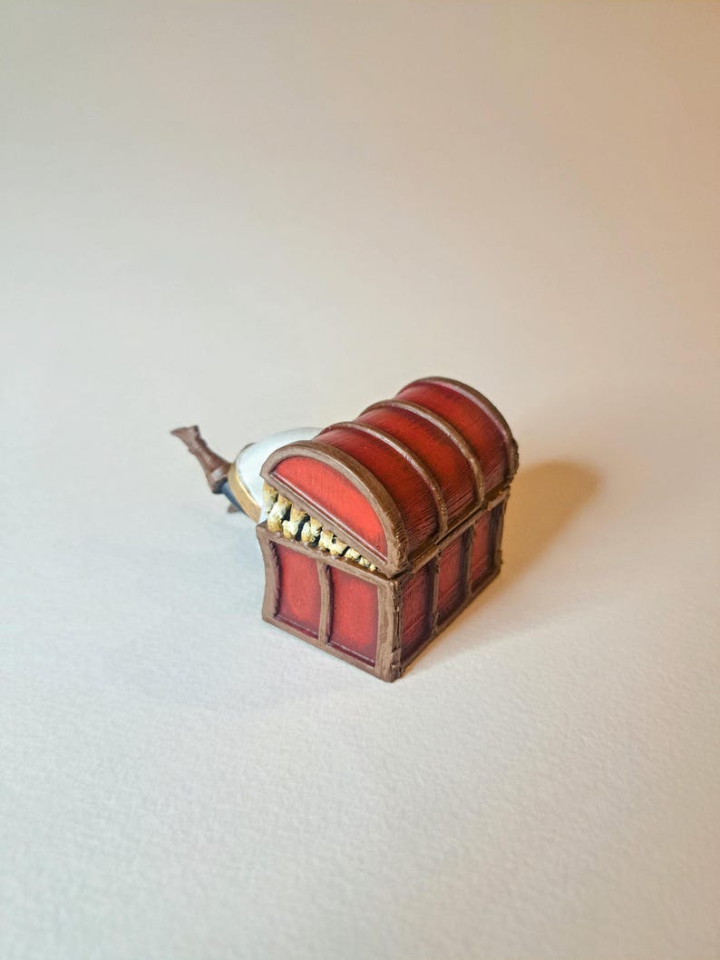 May include: A red wooden treasure chest with gold accents and a hinged lid. The chest is open and the lid is propped up.