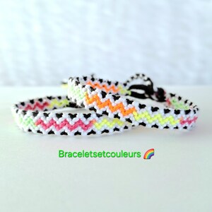 Peut inclure: Deux bracelets d'amitié avec un motif en chevron noir, blanc, rose, orange et vert fluo.