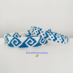 Op de afbeelding: Drie handgemaakte vriendschapsarmbanden met een geometrisch patroon in wit en blauw. De armbanden zijn gemaakt van geweven draad en worden gepresenteerd op een witte ondergrond. De tekst "Braceletsetcouleurs" is zichtbaar.