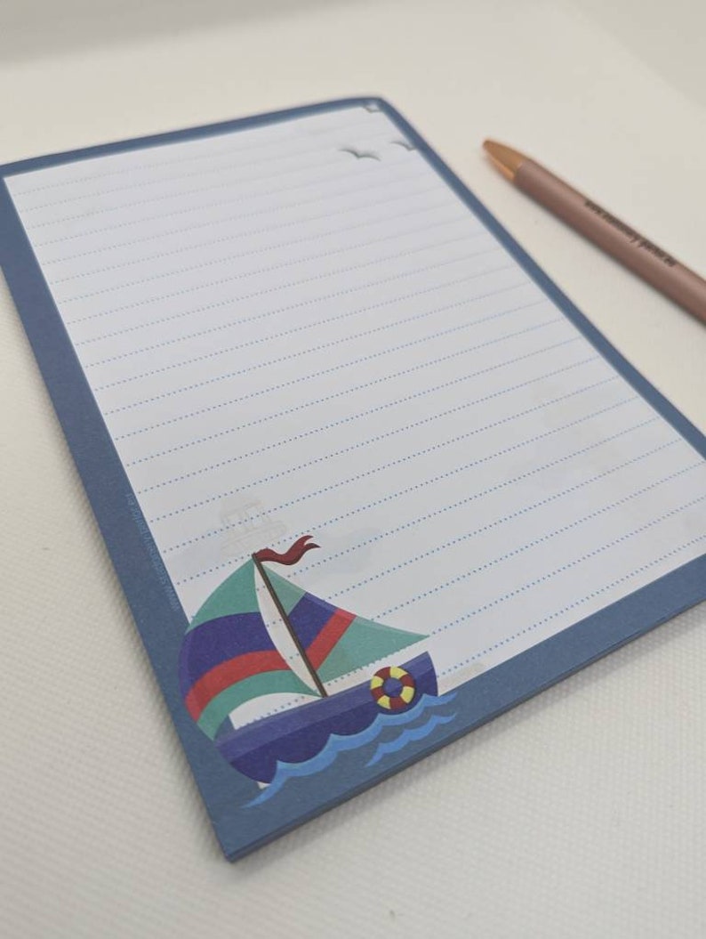 May include: A blue notepad with lined paper and a sailboat illustration. The sailboat is blue, green, red, and yellow. The notepad has a blue border.