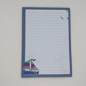 May include: Blue lined notepad with a sailboat and seagulls on the front.