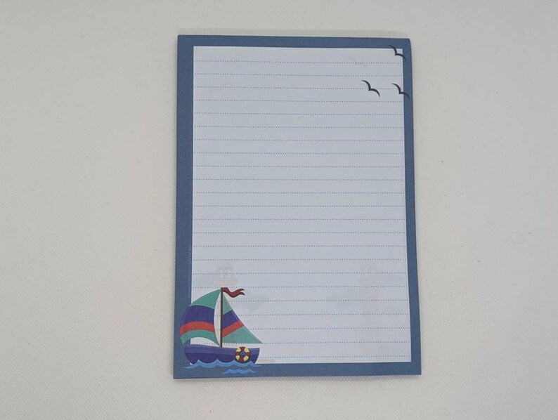 May include: Blue lined notepad with a sailboat and seagulls on the front.