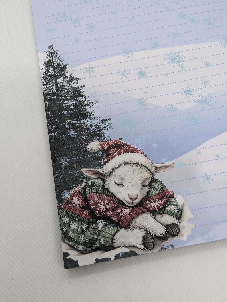 May include: A stationery sheet featuring a sleeping lamb wearing a red and white Santa hat and a green and red sweater. The background shows a snowy landscape with a tall evergreen tree.