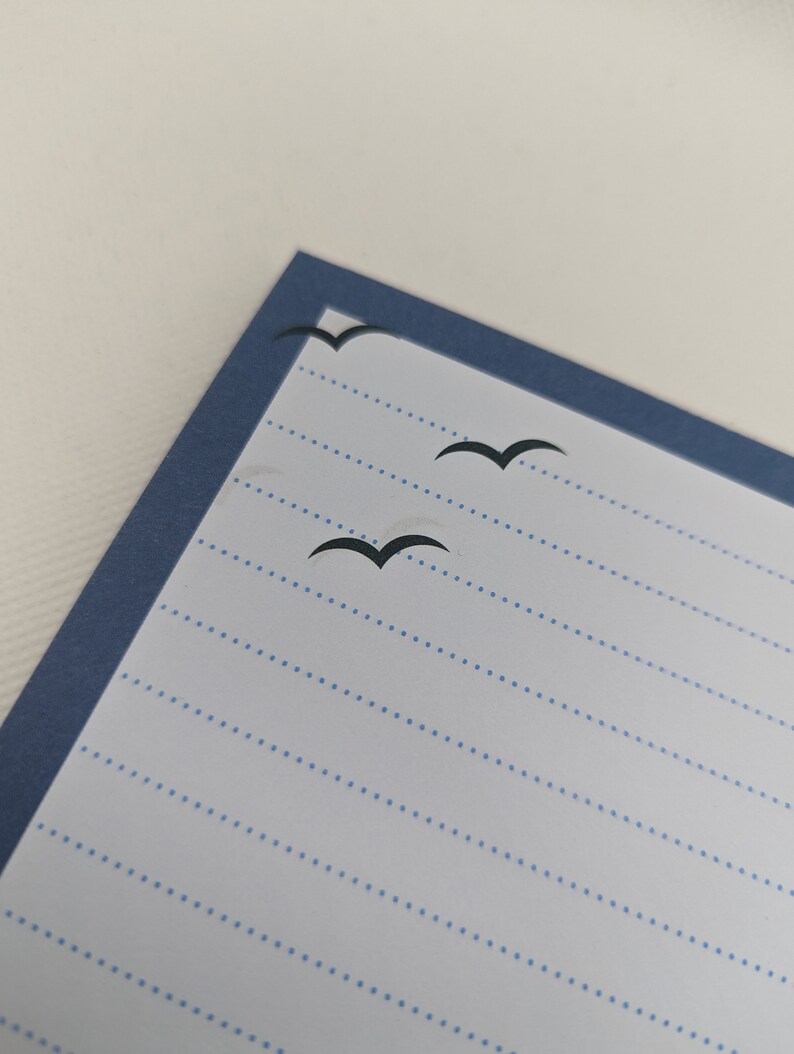 May include: A blue lined notebook with a blue border and three black bird silhouettes flying across the page.