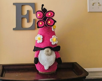 Crochet pink gnome with pink butterfly and daisies.