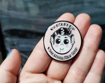 May include: A round button with a light pink background featuring a cartoon vampire with black hair and the text "VAMPIRES WILL NEVER HURT YOU" in a black font. The vampire has a small drop of blood.