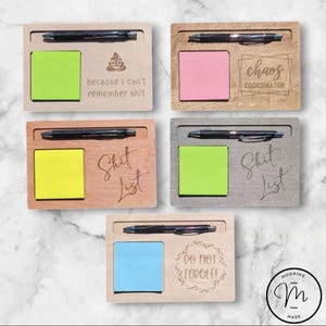 Peut inclure: Organisateurs de bureau en bois avec un stylo, des notes autocollantes et du texte gravé. Les organisateurs sont de différentes couleurs et comportent des phrases comme "because I can't remember shit" et "Chaos Coordinator."