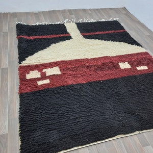 May include: A black, red, and white Moroccan rug with a geometric design. The rug has a thick pile and is made of wool.
