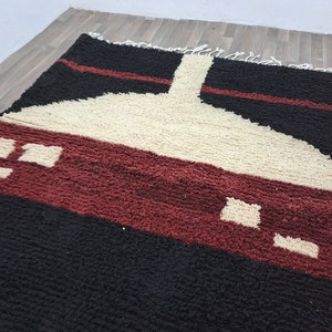May include: A geometric patterned rug with black, white, and burgundy colors. The rug has a modern design with a large white shape in the center.
