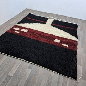May include: A black, red, and white geometric patterned rug with a unique design. The rug is made of wool and has a soft, plush texture.
