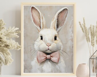 Könnte beinhalten: Gerahmtes Gemälde eines weißen Kaninchens mit langen Ohren und einer rosa Schleife. Das Kaninchen hat ein weiches, flauschiges Aussehen und ist vor einem neutralen Hintergrund platziert. Das Kunstwerk wird auf einem weißen Regal mit dekorativen Elementen ausgestellt.